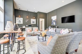 A living room with a grey couch and a television on the wall.